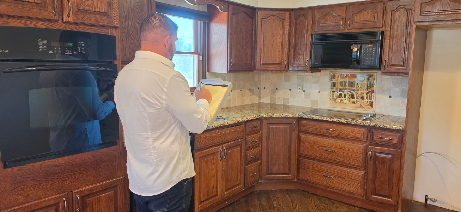 Andrew Ragusa taking notes on a clipboard while walking through a kitchen during a property evaluation